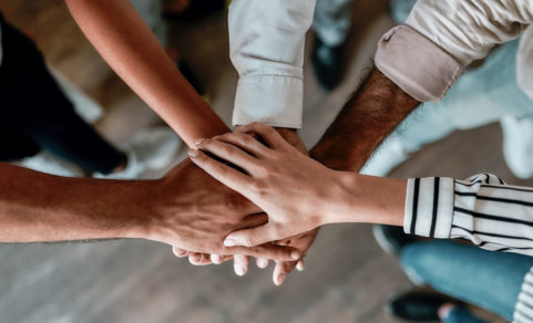 Cooperation. Top view of people holding hands together while standing in the office